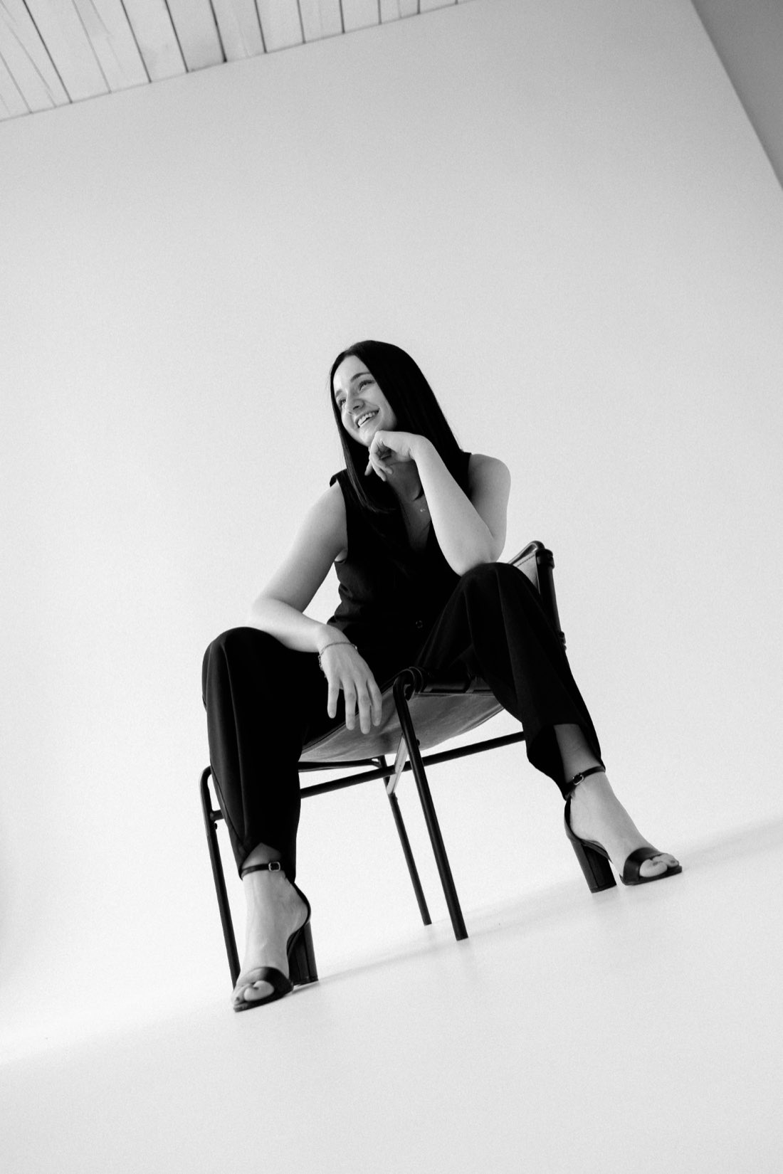 Dani smiling, seated on a sling chair in the studio