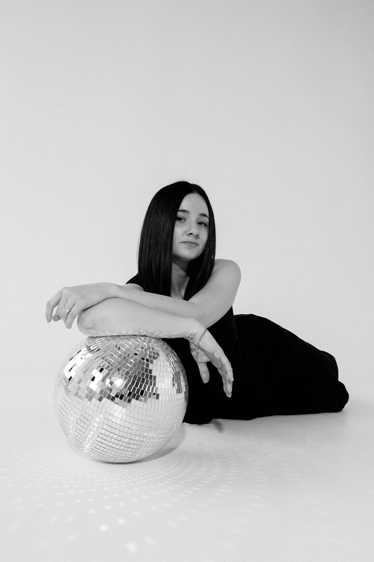 Dani lying on the floor with her arms resting on a large disco ball
